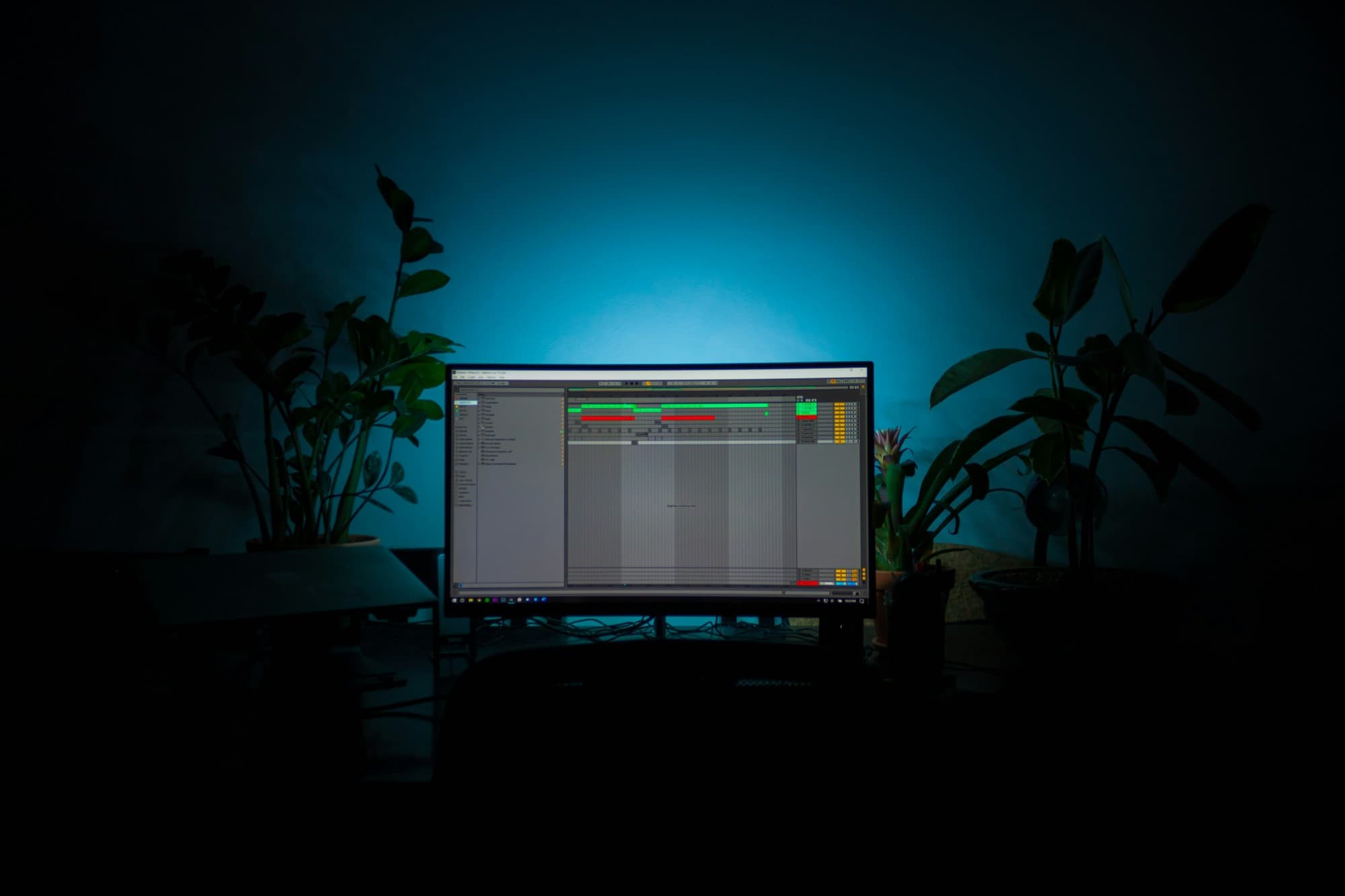 Studio desk at night, Ableton on a single monitor lit by a blue wall, plants either side